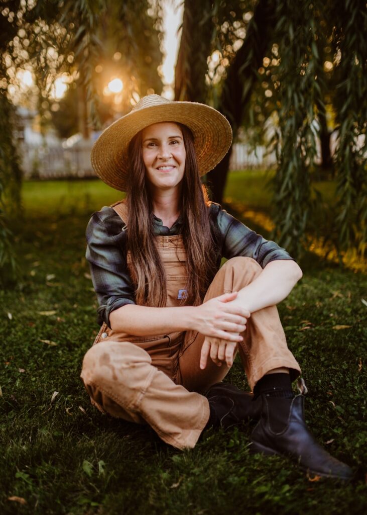 Photo by Amie Roussel A woman sitting on the ground wearing a hat